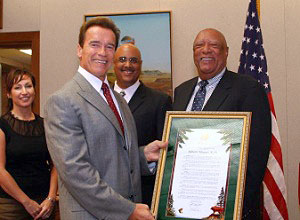 California Governor Arnold Schwarzenegger admires the Senate Resolution presented to Sylester Flowers on September 5, 2007, while son Eric Flowers and his wife look on.